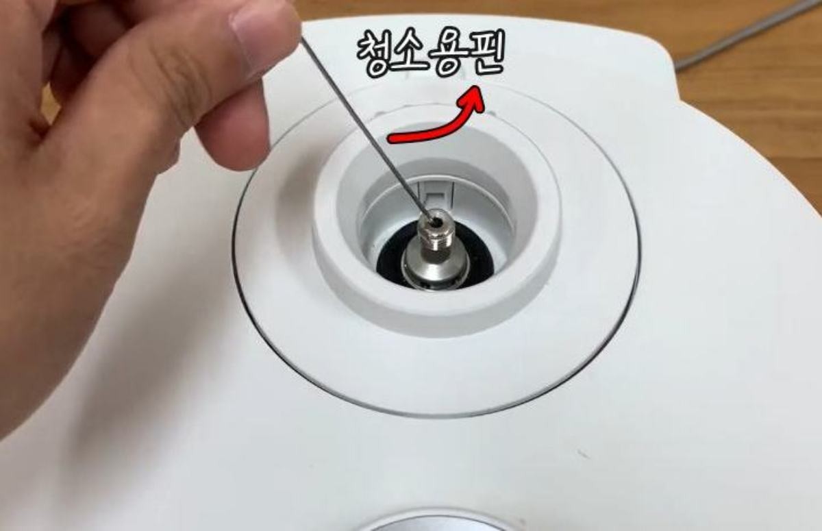 밥솥 바닥에 부착된 청소용핀으로 안쪽 이물질을 청소하는 모습. / 유튜브 '쿠쿠서비스'