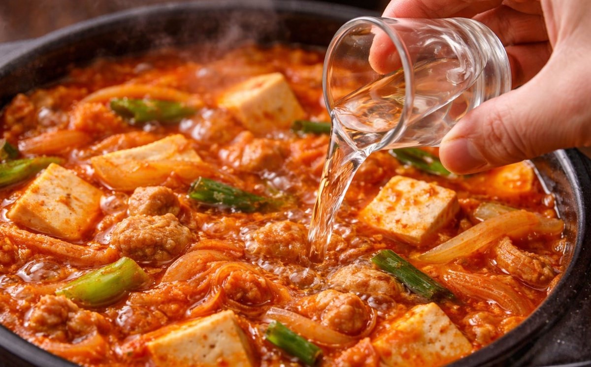 김치찌개에 소주를 약간만 넣는 모습. 기사 이해를 돕기 위해 AI를 활용해 제작한 자료 사진. 적절한 양의 소주는 김치찌개의 맛을 해치지 않으면서도 전체적인 완성도를 높이는 역할을 한다.