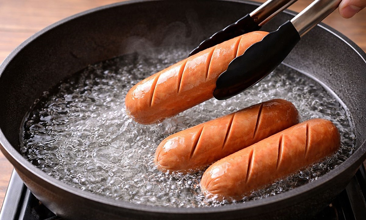 소시지를 끓는 물에 굽는 모습. 기사 이해를 돕기 위해 AI를 활용해 제작한 자료 사진. 달구어진 프라이팬에 물을 먼저 넣고 소시지를 익히는 방법은 훨씬 효율적인 조리법으로 알려져 있다. 프라이팬에 기름 대신 물을 사용하면 소시지 전체에 열이 보다 고르게 전달돼 속까지 안정적으로 익는다.