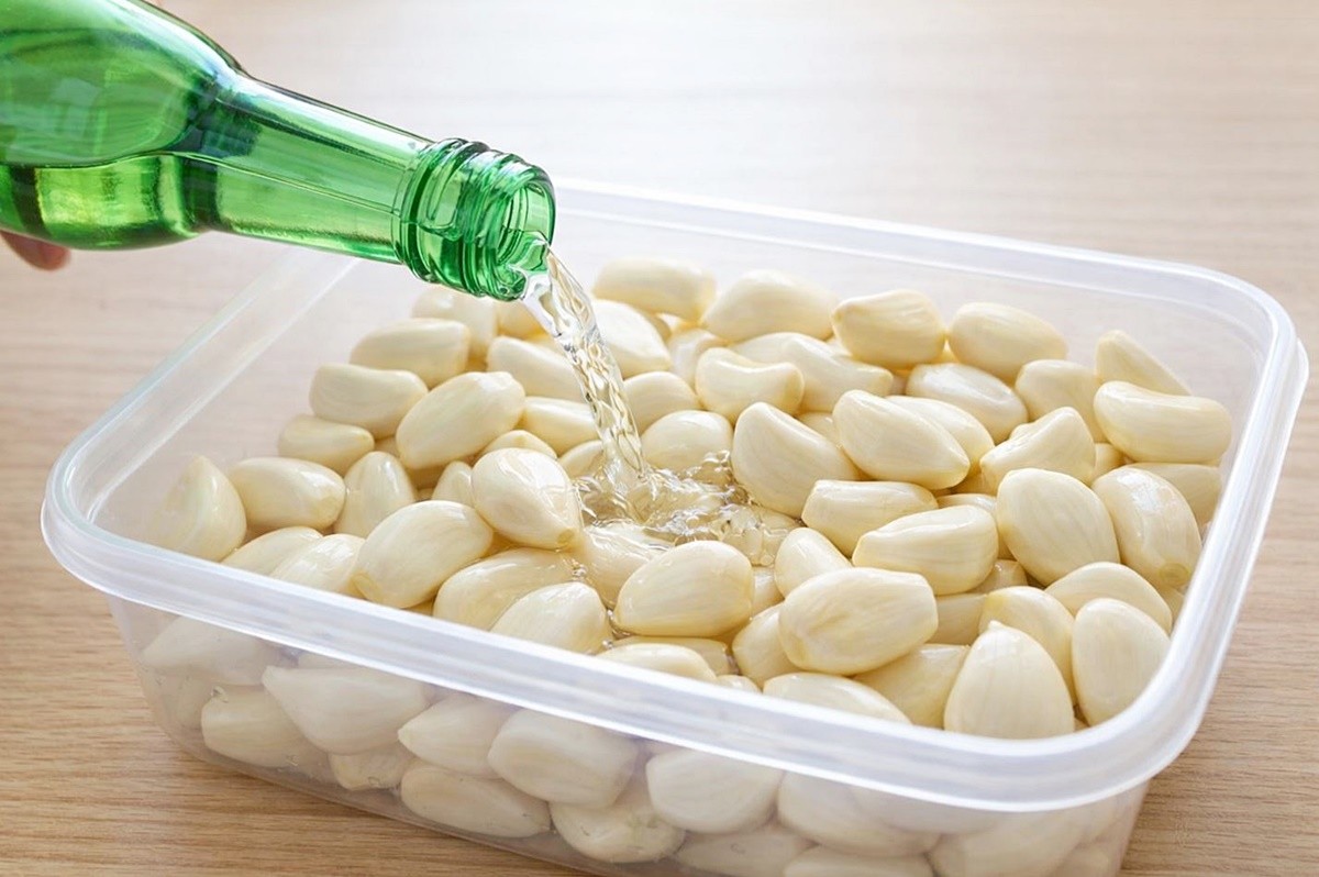 마늘에 소주를 붓는 모습. 기사 이해를 돕기 위해 AI를 활용해 제작한 자료 사진입니다. 실제 모습과 다소 차이가 있을 수 있습니다.