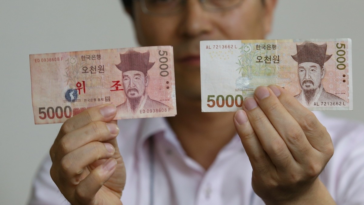 한국은행 관계자가 오천원권 진폐(오른쪽)와 위폐를 비교하고 있다. 기사의 이해를 돕기 위한 사진 / 연합뉴스