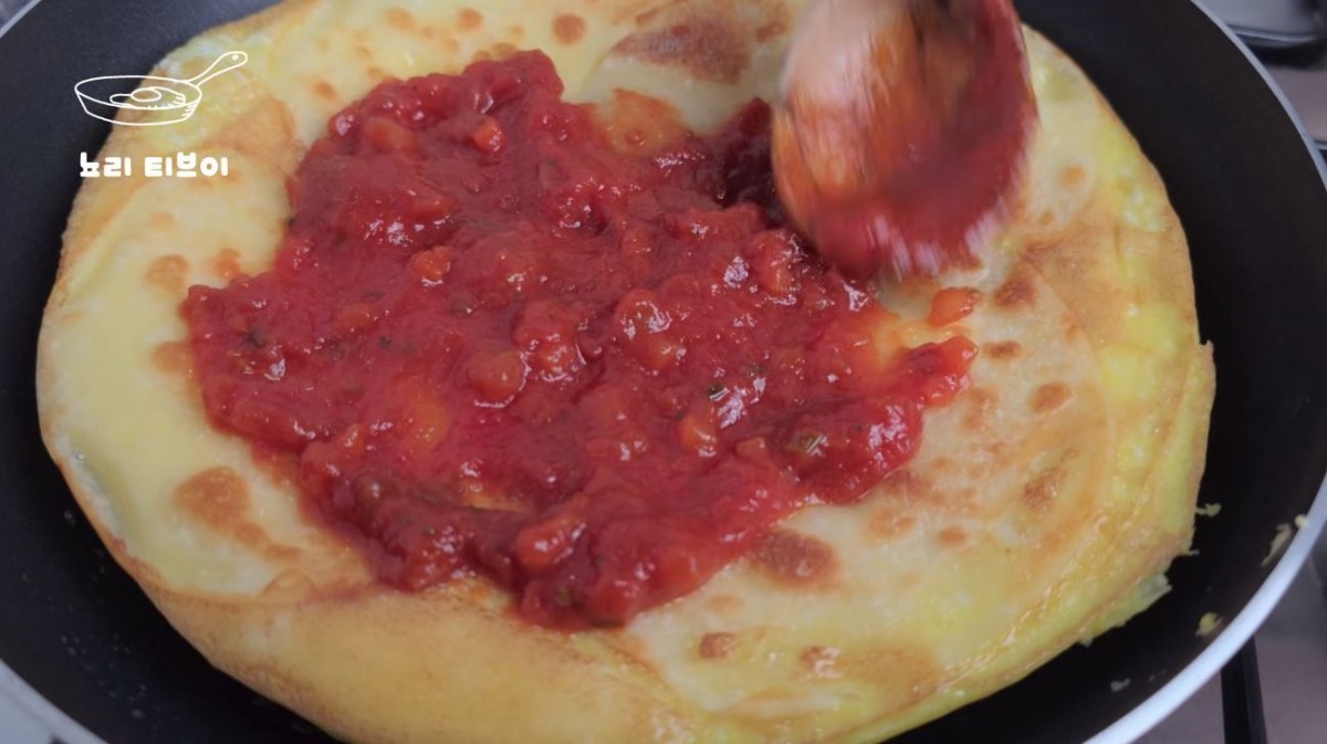 계란물을 부은 만두피 위에 토마토 소스를 바르는 모습. / 유튜브 '뇨리 티브이'