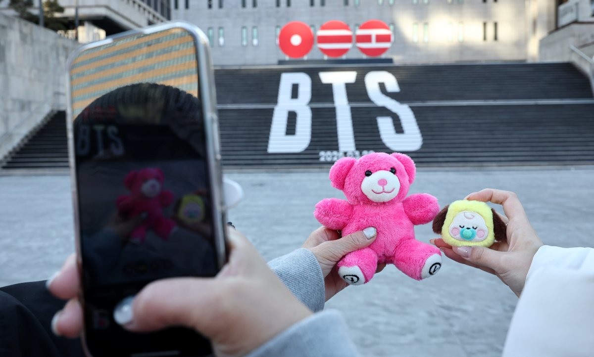 서울 종로구 세종문화회관 계단에 설치된 방탄소년단 정규 5집 컴백을 알리는 홍보물을 배경으로 관광객들이 기념 촬영하는 모습. / 뉴스1