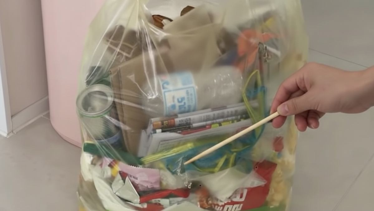 종량제 봉투 하단을 젓가락으로 찔러 공간을 확보한다 (AI로 제작됨)