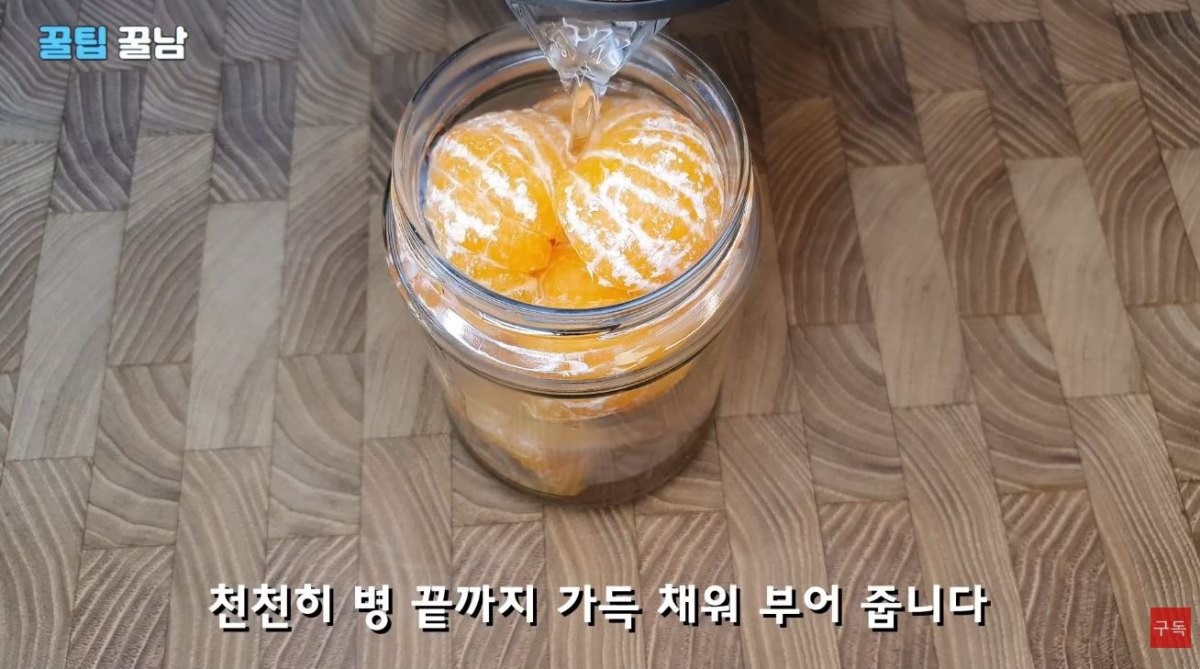 귤이 들어있는 유리병에 뜨거운 물을 붓는 모습. / 유튜브 '꿀팁알려주는남자, 꿀팁꿀남 Honey tips man'