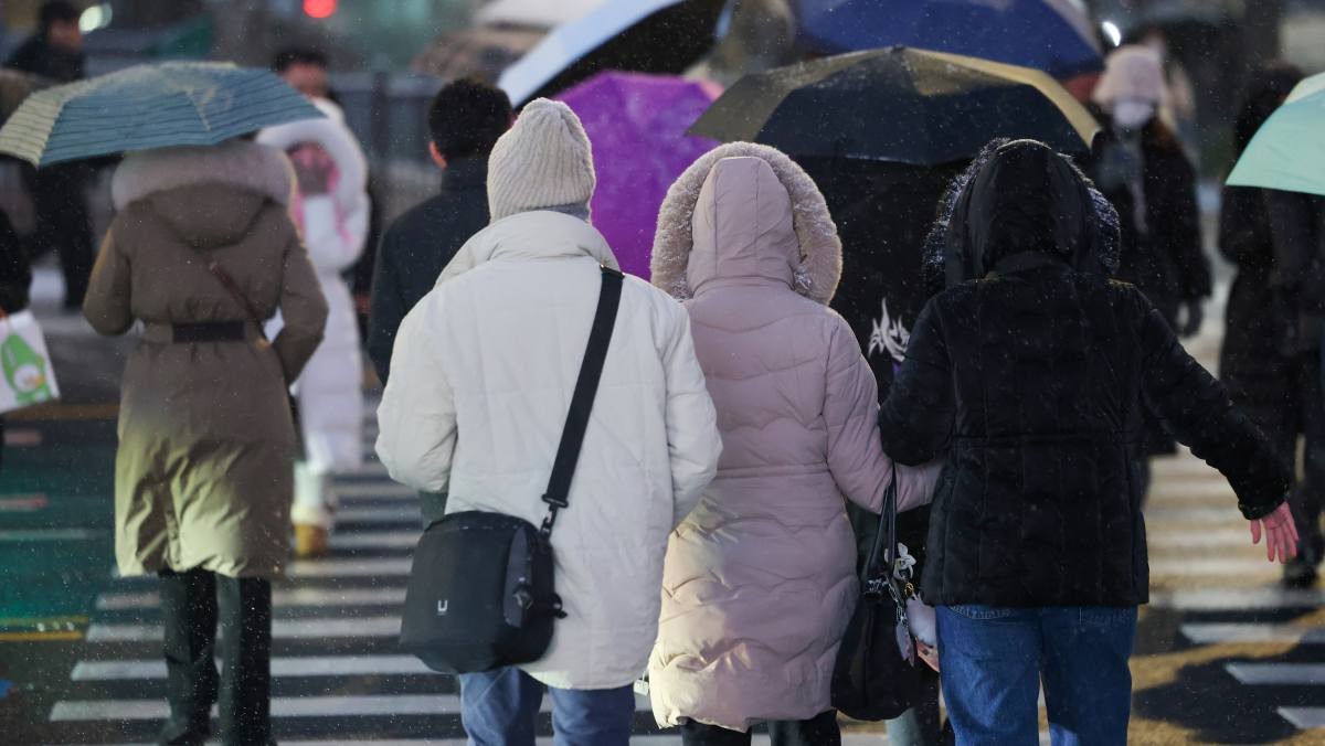서울 종로구 광화문광장 버스정류장에서 시민들이 외투 모자나 우산을 쓰고 이동하고 있다.  / 연합뉴스