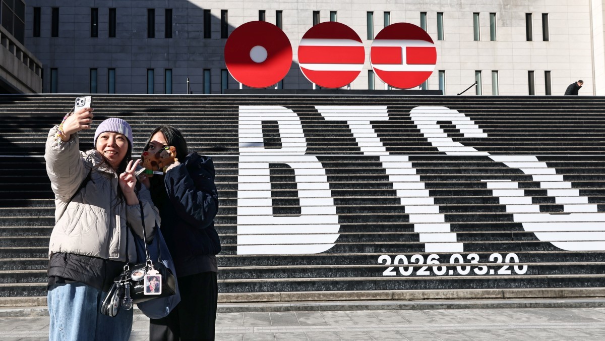 서울 종로구 세종문화회관 계단에서 홍콩에서 온 관광객들이 오는 3월 3년 9개월 만에 '완전체'로 돌아오는 그룹 방탄소년단(BTS)의 컴백을 알리는 홍보물을 기념촬영하고 있다. / 연합뉴스