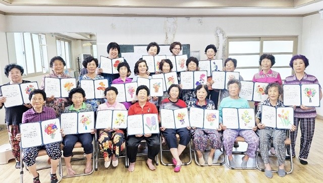 황전 비촌마을 주민들이 ‘마을자원기록’ 프로그램의 일환으로 마을 달력에 삽입될 그림을 완성한 뒤, 단체 기념사진을 촬영하고 있다.