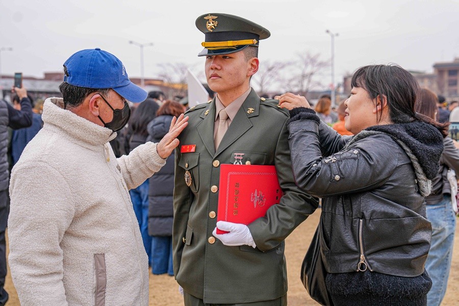 임관식 후 부모님이 임관한 신임 부사관 아들 정복에 계급장을 달아주고 있다.