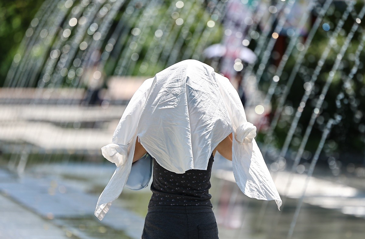 폭염 속 서울 광화문광장에서 한 시민이 옷으로 얼굴을 가린 채 이동하고 있다. 기사 이해를 돕기 위한 자료 사진 / 뉴스1