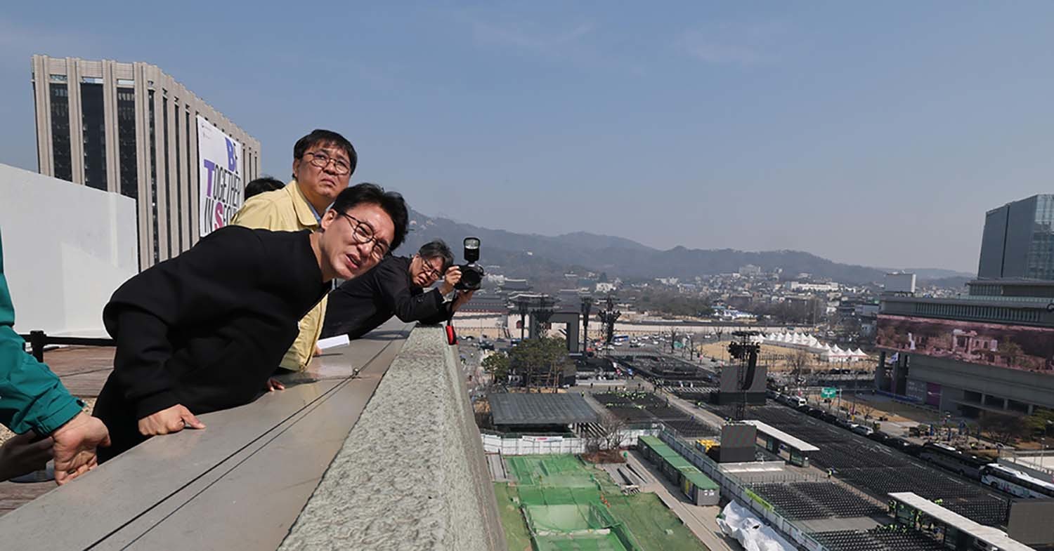김민석 국무총리가 21일 오전 서울 종로구 세종문화회관 옥상에서 BTS 컴백공연 무대가 설치된 광화문광장을 살펴보고 있다. / 뉴스1