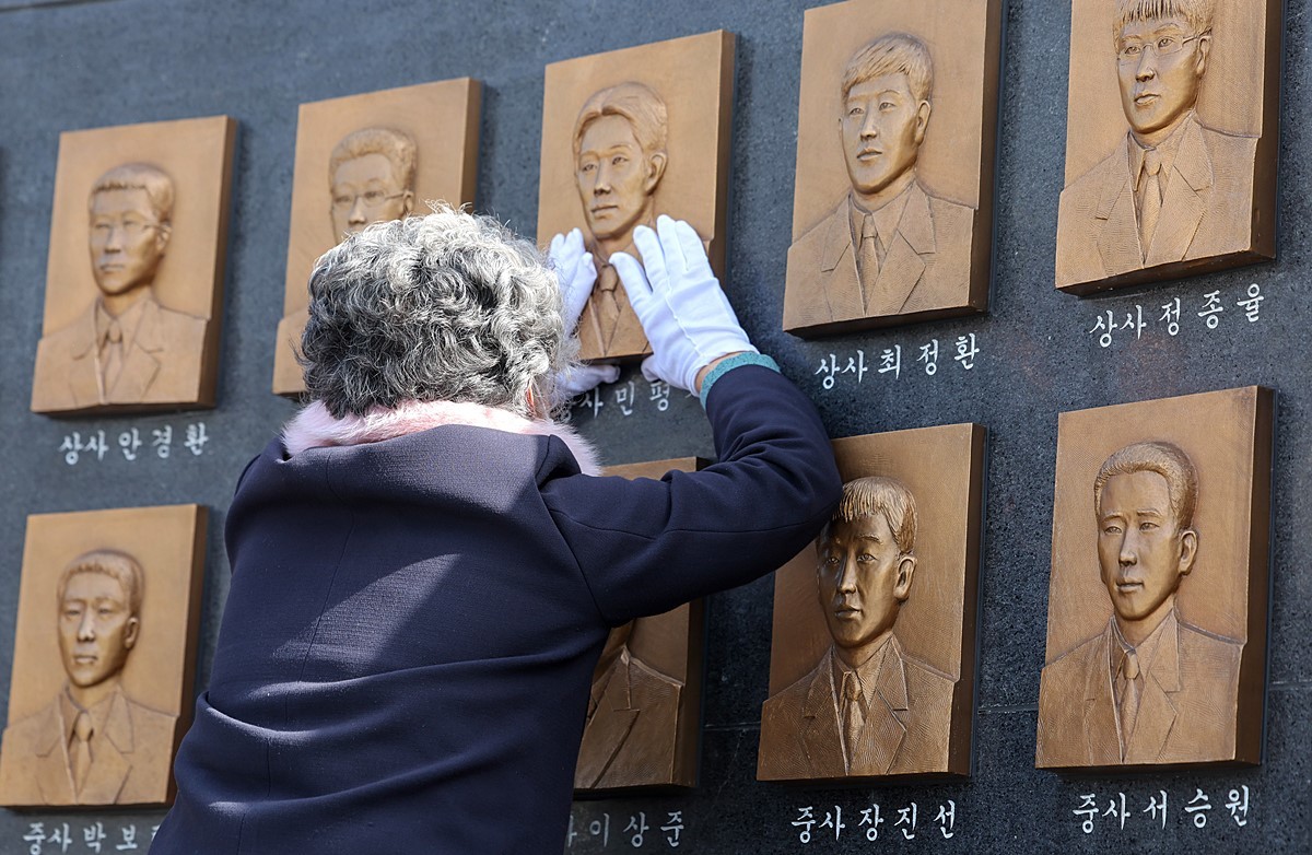 '천안함 46용사 추모식'에서 한 유가족이 추모비에 새겨진 얼굴을 어루만지고 있다. 자료 사진 / 연합뉴스
