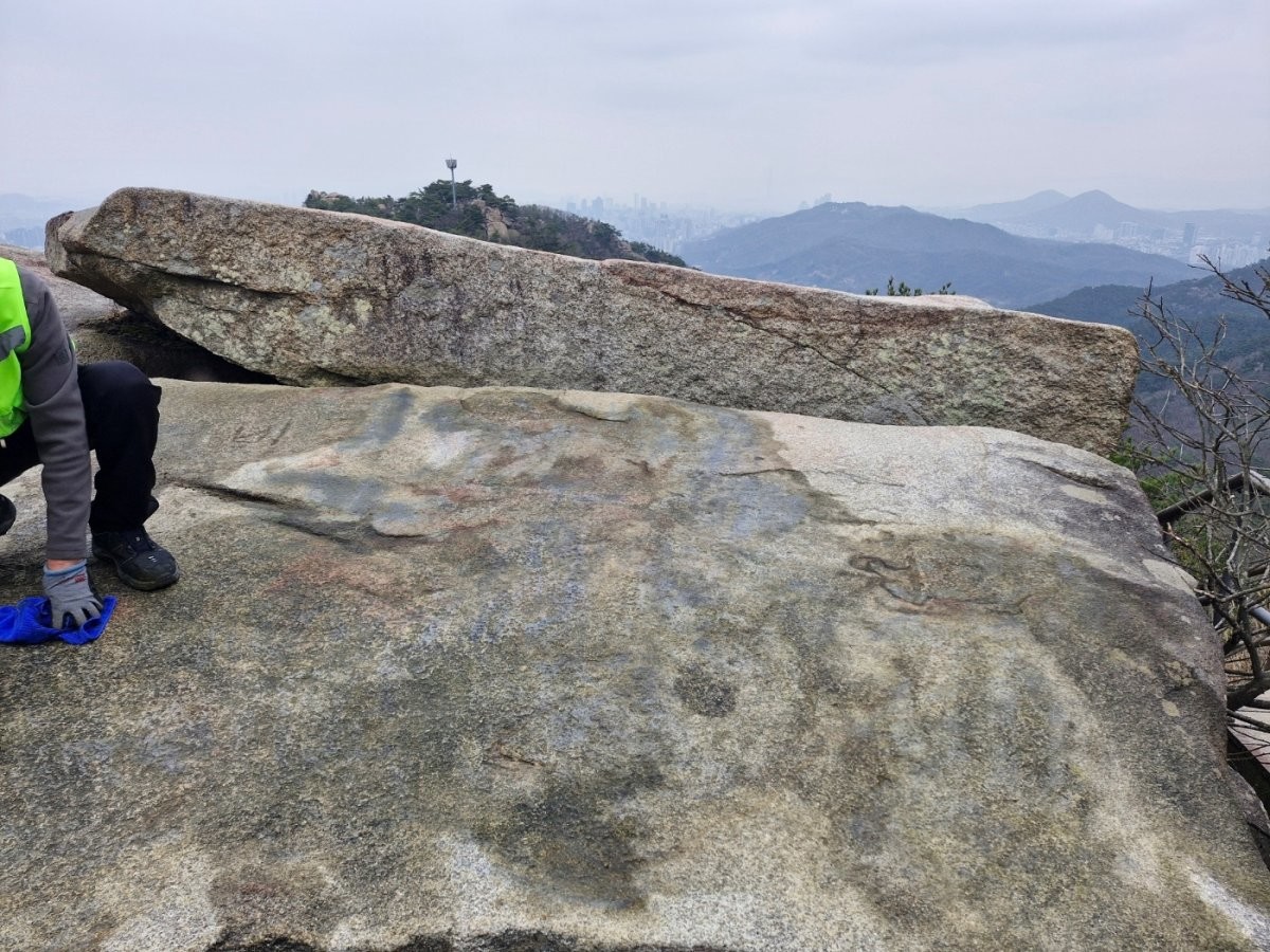 래커 낙서로 인해 훼손된 관악산 마당바위를 복원 중인 모습. / 관악구청 제공, 뉴스1