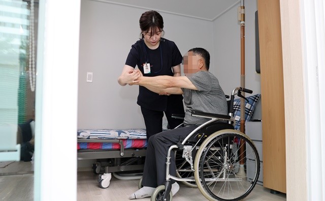 광산구 ‘살던집 프로젝트’ 기반 시설인 ‘중간집’에서 생활하는 주민이 작업 치료사의 도움으로 재활 운동을 하고 있다.