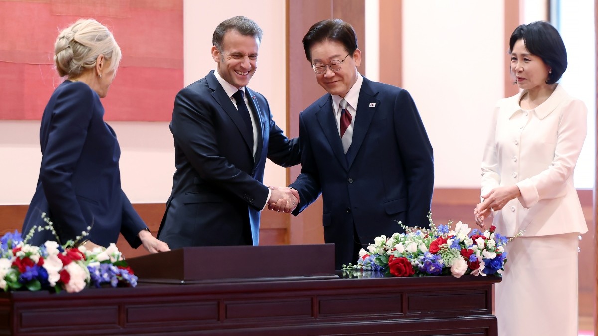 이재명 대통령이 3일 청와대에서 정상회담에 앞서 에마뉘엘 마크롱 프랑스 대통령과 방명록을 보며 악수를 나누고 있다. / 뉴스1