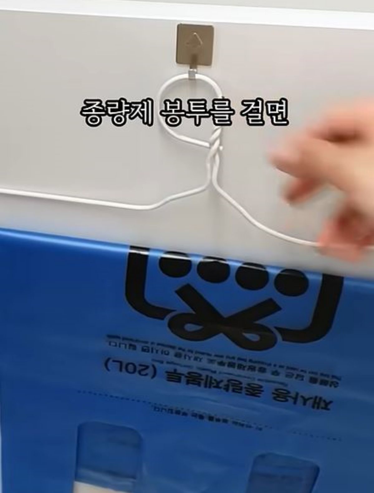 종량제 봉투를 개조한 옷걸이에 걸고 해당 옷걸이를 고리에 걸어 찬장 문 안쪽에 걸어둔 모습. 이 방법대로 종량제 봉투를 보관하면 따로보관 용품을 살 필요 없이 간단하게 보관이 가능하다. 매일 여는 찬장 안 쪽에 보관돼 언제든지 한 장씩 손쉽게 꺼내쓸 수 있는 것도 장점이다. / 유튜브 '집구석구석꿀팁, 집꿀'