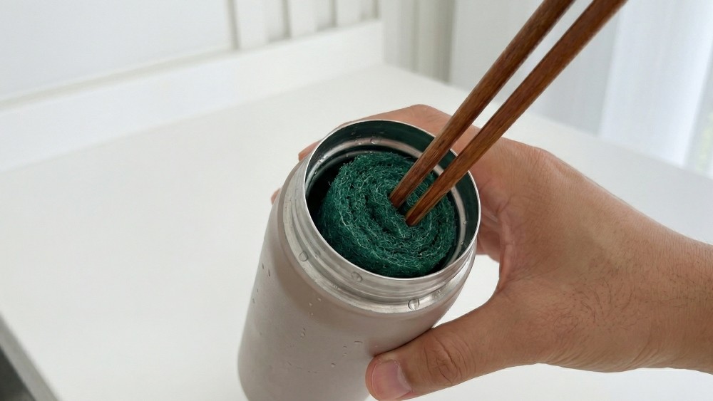 AI가 생성한 자료사진. 말아놓은 수세미 중앙의 공간에 나무젓가락과 같은 긴 막대를 꽂아 넣는다. 고무줄을 이용해 수세미가 풀리지 않도록 단단히 묶어 고정하면 간이 세척 도구가 완성된다.