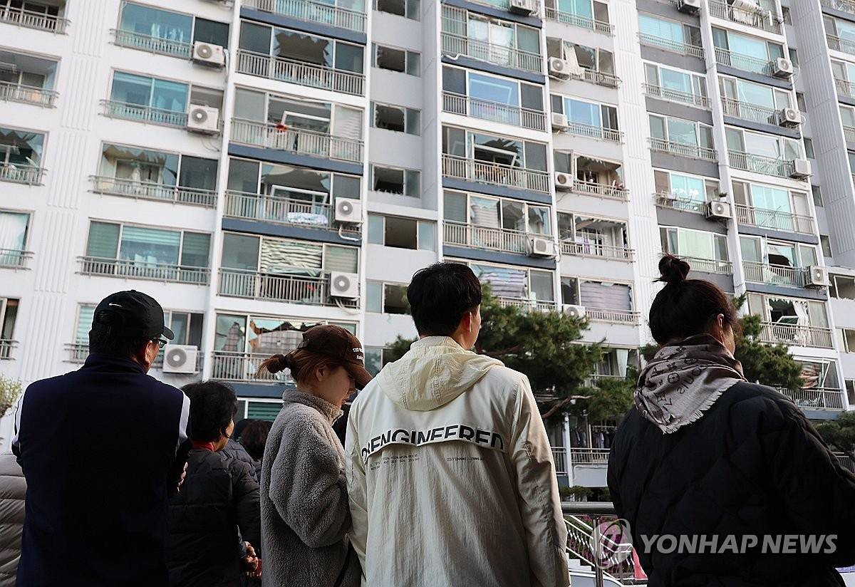 13일 오전 청주시 흥덕구 봉명동의 한 아파트 주민들이 폭발 사고 여파로 깨진 창문을 바라보고 있다 / 연합뉴스