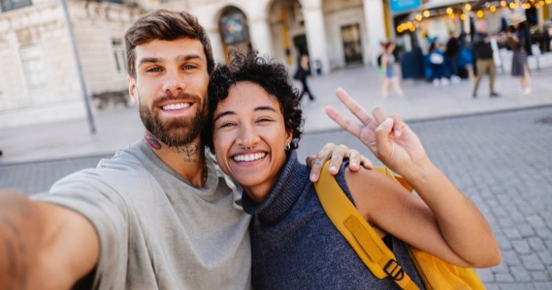 여행지 거리에서 한 커플이 밝은 표정으로 셀카를 찍으며 즐거운 순간을 기록하고 있는 모습이다. / 셔터스톡
