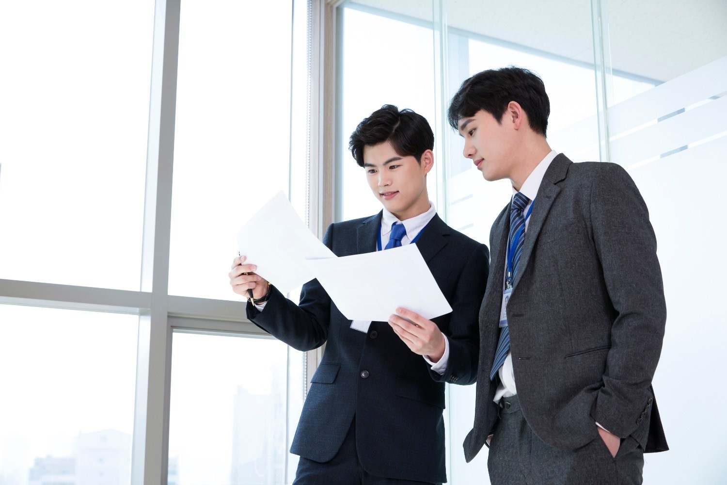 정장을 입은 두 남성이 사무실에서 서류를 함께 확인하며 업무를 논의하고 있는 모습이다. / 셔터스톡