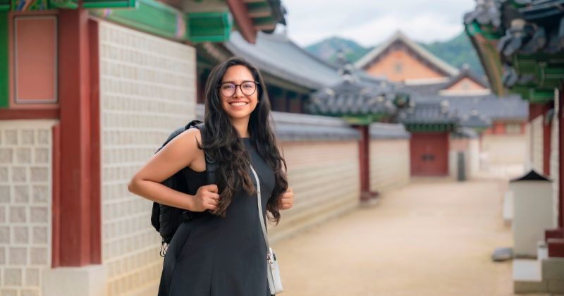 서울 전통 한옥마을 골목에서 배낭을 메고 있는 외국인 여성 관광객. 한국 전통 건축을 배경으로 여행을 즐기는 모습. / 셔터스톡