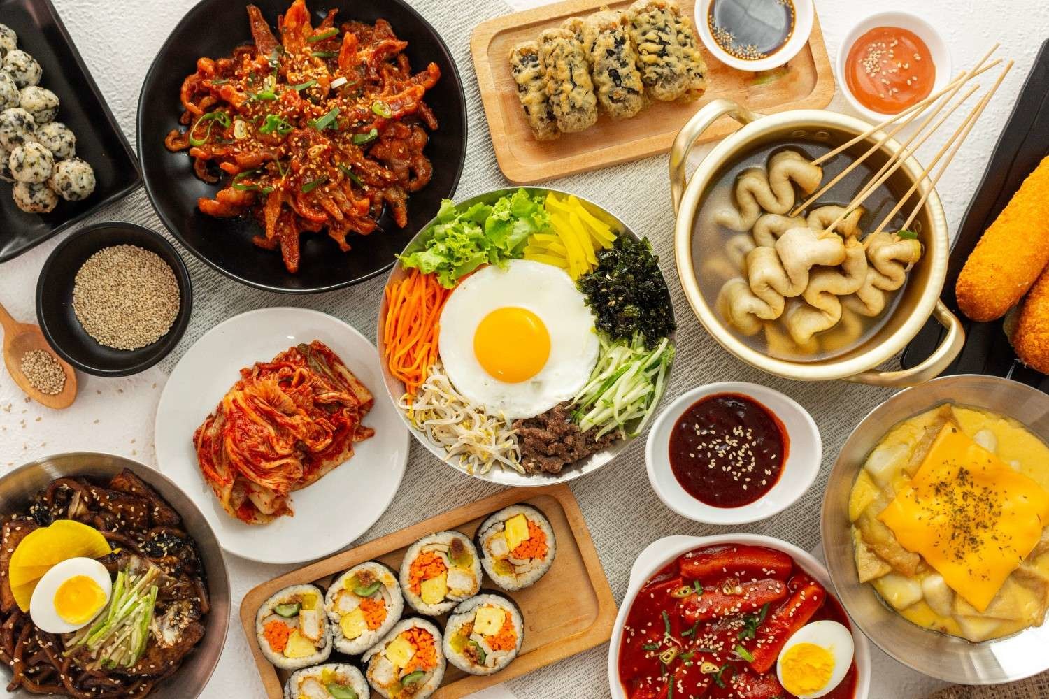비빔밥, 김밥, 떡볶이, 어묵, 김치 등 다양한 한국 전통 음식이 한 상에 차려진 모습. 색감이 풍부한 한식 메뉴와 길거리 음식이 조화를 이루는 푸드 테이블. / 셔터스톡