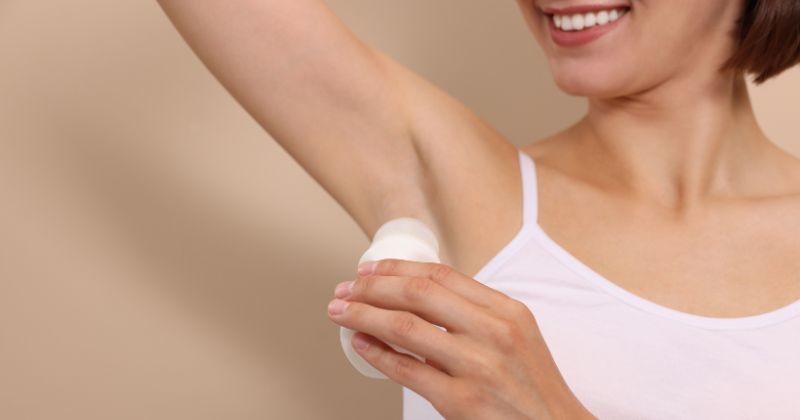 베이지 배경, 클로즈업에 롤-온 데오도란트를 적용 하는 웃는 여자 / 셔터스톡