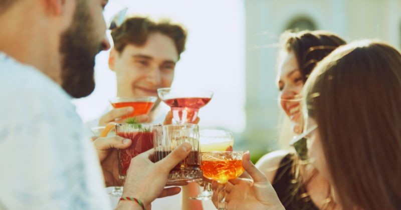 태양의 황금빛이 친구들 사이에서 경쾌한 토스트를 향상시키며, 그들의 음료는 빛난다 / 셔터스톡