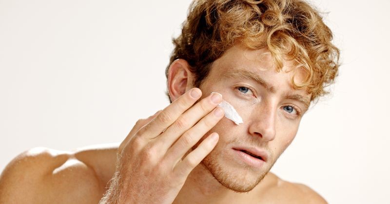 노화 방지 치료를 위해 얼굴에 크림을 바르는 스튜디오에서 사람의 아름다움, 로션 및 초상화. 얼굴 제품 적용을 위해 흰색 배경에 절연 된 모델로 수분, 보습제 및 스킨케어 / 셔터스톡