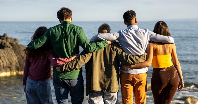 다문화 그룹의 친구들이 포옹하고 바다를 바라보는 후면 관점으로, 단결, 자유, 포용성을 상징한다. / 셔터스톡