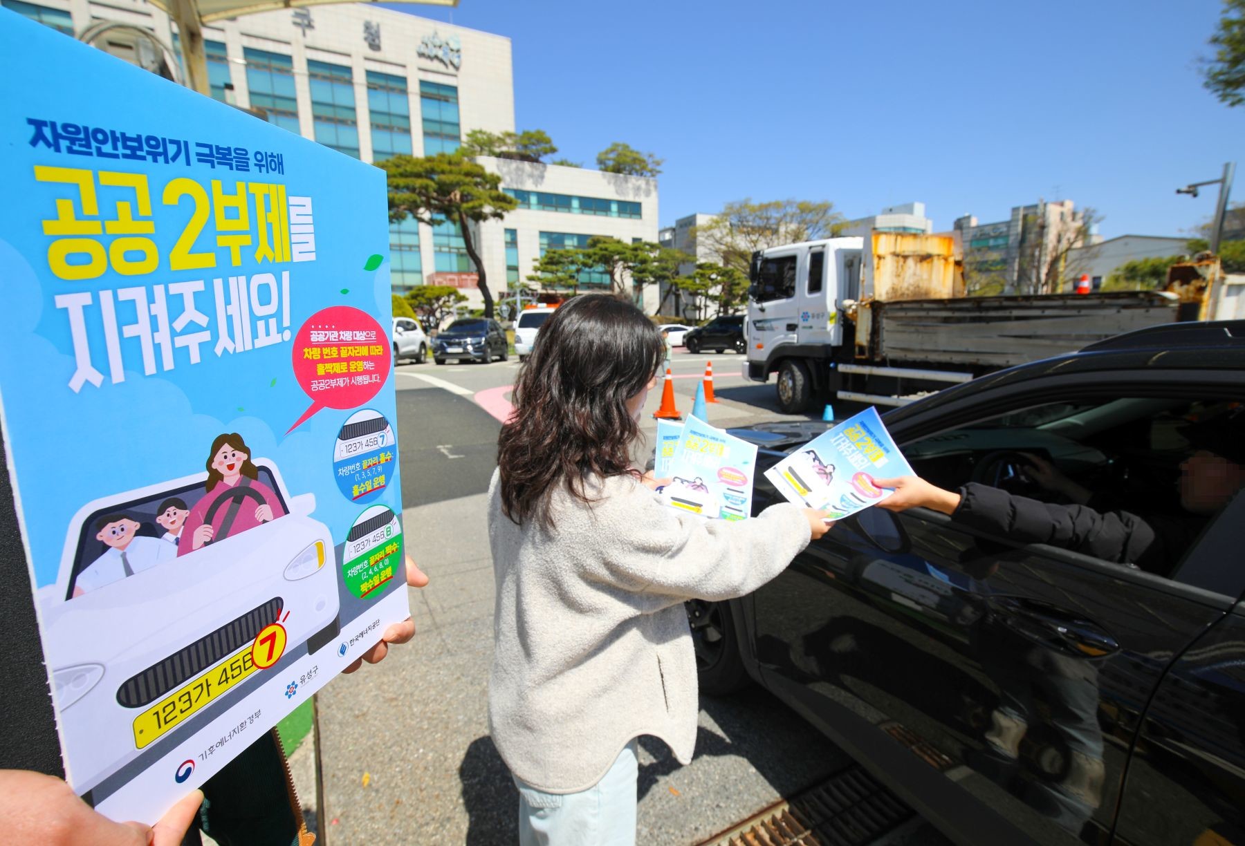 유성구청 직원이 구청 출입 차량에 공공2부제 홍보물을 배부하고 있다. / 사진=대전 유성구