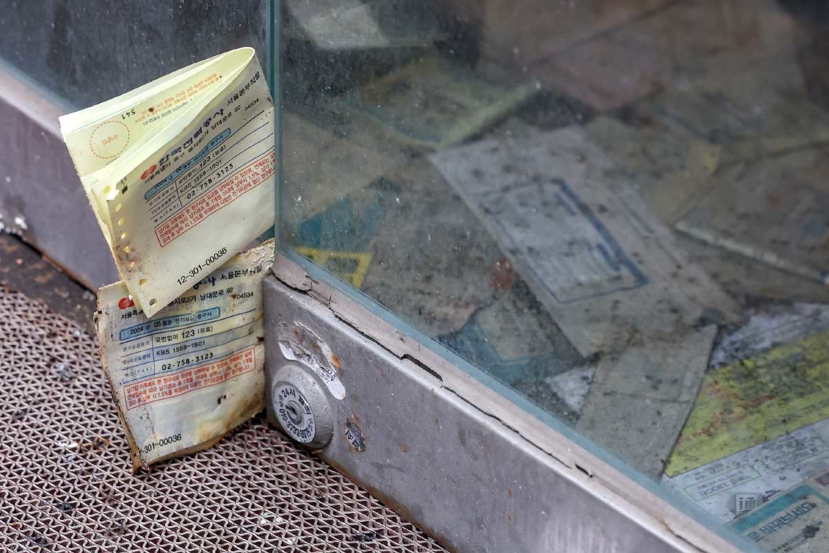 서울 중구 명동의 한 폐업한 상점 문틈 사이에 전기요금 고지서가 꽃혀 있다. / 뉴스1