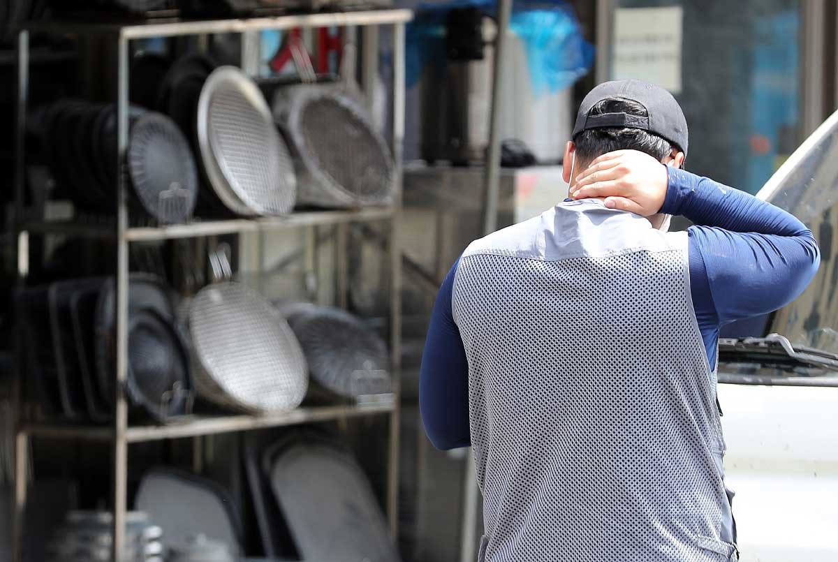 서울 황학동 주방거리에서 고개를 숙인 소상공인 뒤로 폐업한 점포에서 나온 중고 주방용품이 잔뜩 쌓여있다. / 뉴스1