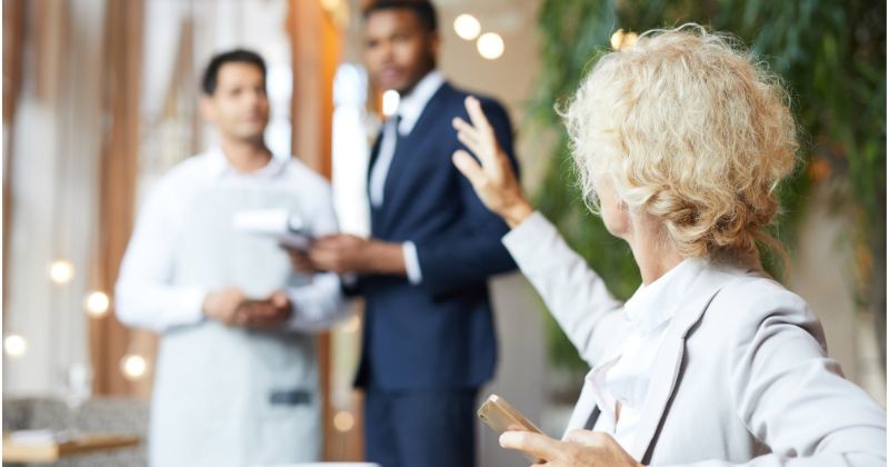 금발의 사업가 점심에 식당에 앉아 웨이터를 부르다 / 셔터스톡