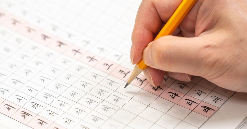 학습지에 한국어 글자를 연습하는 손 / 셔터스톡