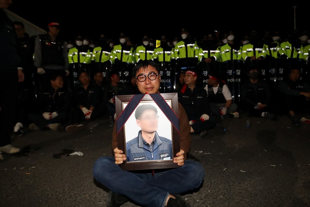 지난 20일 경남 진주시 정촌면 CU 진주물류센터 앞에서 화물연대 노조원이 집회 중 2.5톤 화물차에 치어 숨진 노조원의 영정을 들고 슬픔에 잠겨 있다. 이날 현장에서는 화물차와 집회 참가자 3명이 충돌해 1명이 숨지고 2명이 다치는 사고가 발생했다. / 뉴스1