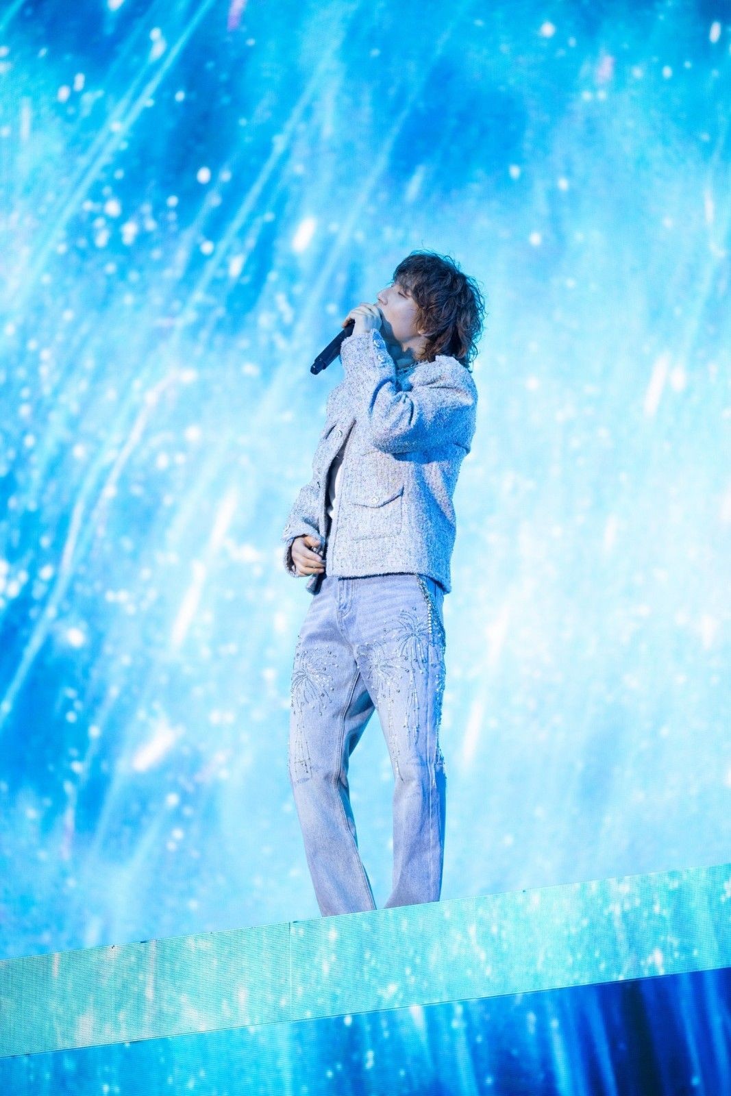 푸른 조명이 가득한 무대 위에서 대성이 감성적인 분위기 속에 노래를 이어가고 있다. 몽환적인 배경과 어우러진 섬세한 보컬 표현이 인상적인 장면이다. / 알앤디컴퍼니