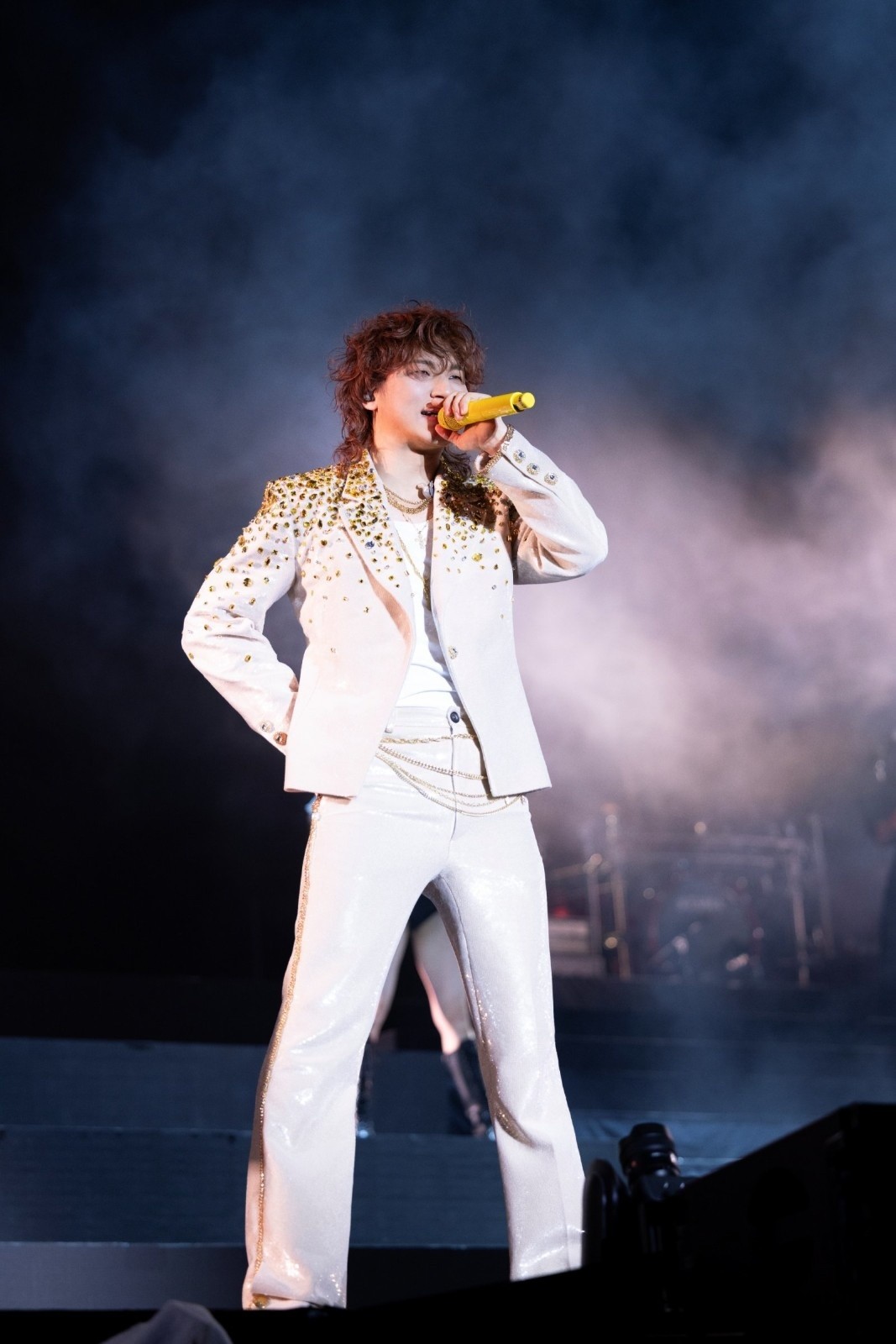 무대 위에서 화려한 화이트 의상을 입은 가수 대성이 마이크를 들고 열정적인 퍼포먼스를 펼치고 있다. 강렬한 조명과 함께 특유의 에너지 넘치는 무대 장악력이 돋보이는 순간이다. / 알앤디컴퍼니