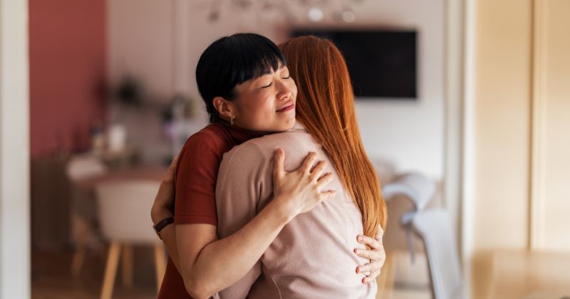 아늑한 실내 환경에서 우정, 배려, 지원 센터를 상징하며 따뜻하게 껴안고 있는 두 여성의 모습이 감동적인 순간이다. 이 이미지는 강한 연결, 연민, 애정의 감정을 전달한다. / 셔터스톡