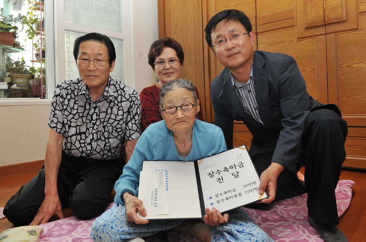 기사 이해를 돕기 위한 참고사진. 김성환 노원구청장(오른쪽)이 지난 2012년 서울 상계동 송안옥(101세) 할머니께 장수축하금을 전달하고 가족들과 기념촬영을 하고 있다. 노원구는 기대수명이 늘어남에 따라 100세 이상 어르신에게 건강과 장수를 기원하고 경로효친의 사회적 분위기를 조성하고자 장수축하금과 장수축하용품을 전달하는 행사를 마련했다. (노원구 제공)  / 뉴스1