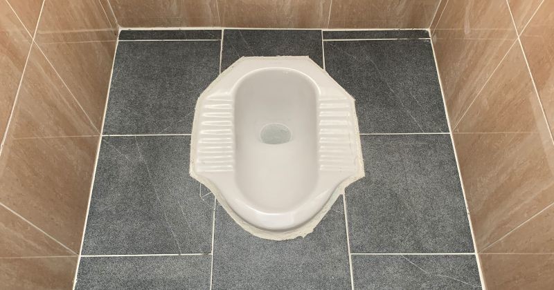 바닥타일은 공장에서 일하는 노동자들을 위한 쪼그리고 앉은 형태의 화장실을 둘러싸고 있습니다. / 셔터스톡