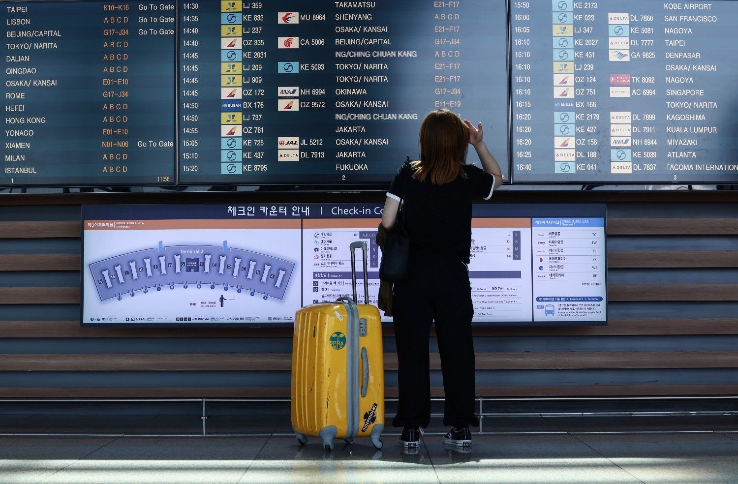 공항 출발 안내 전광판 앞에서 한 여행객이 항공편 정보를 확인하고 있다. 커다란 캐리어를 옆에 두고 탑승 게이트를 찾는 모습이다. / 뉴스1