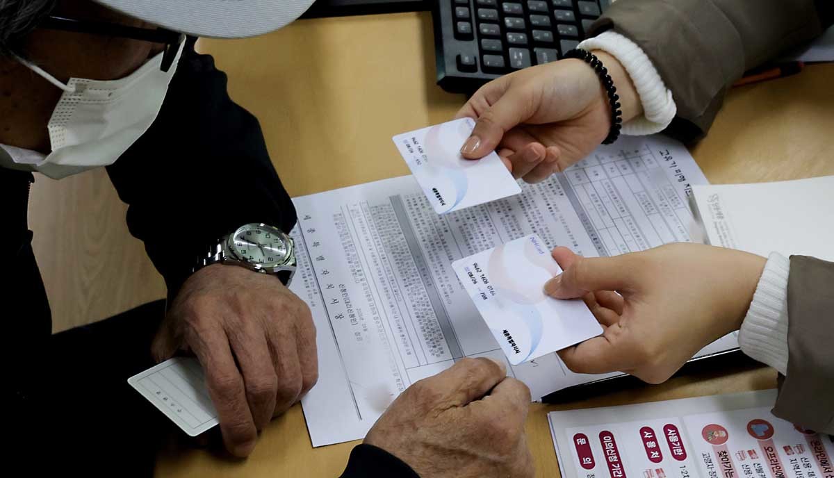 고유가 피해지원금 1차 지급이 시작된 27일 세종시 북세종통합행정복지센터에 마련된 지원금 접수처에서 신청 접수를 마친 시민이 2장의 카드에 나누어 지원금을 수령하고 있다.  / 뉴스1