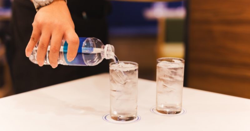 웨이터는 보텔에서 나온 물을 식당의 유리에 붓는다. / 셔터스톡