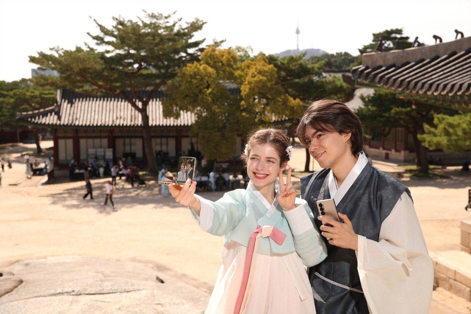 한복을 입은 외국인 커플이 서울의 전통 궁궐을 배경으로 셀카를 찍고 있다. 한국 전통문화 체험을 즐기는 모습이 인상적이다. / 뉴스1