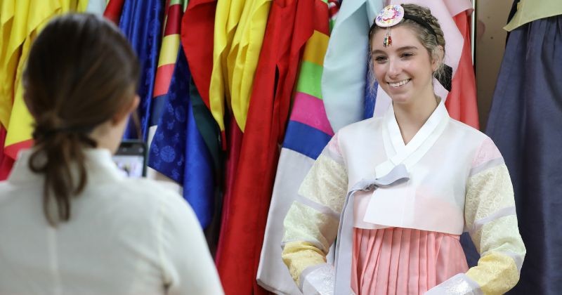 한복을 입은 외국인 여성이 환하게 웃으며 사진을 촬영하고 있다. 다양한 색상의 한복이 걸린 매장에서 한국 전통 의상을 체험하는 모습이다 / 뉴스1