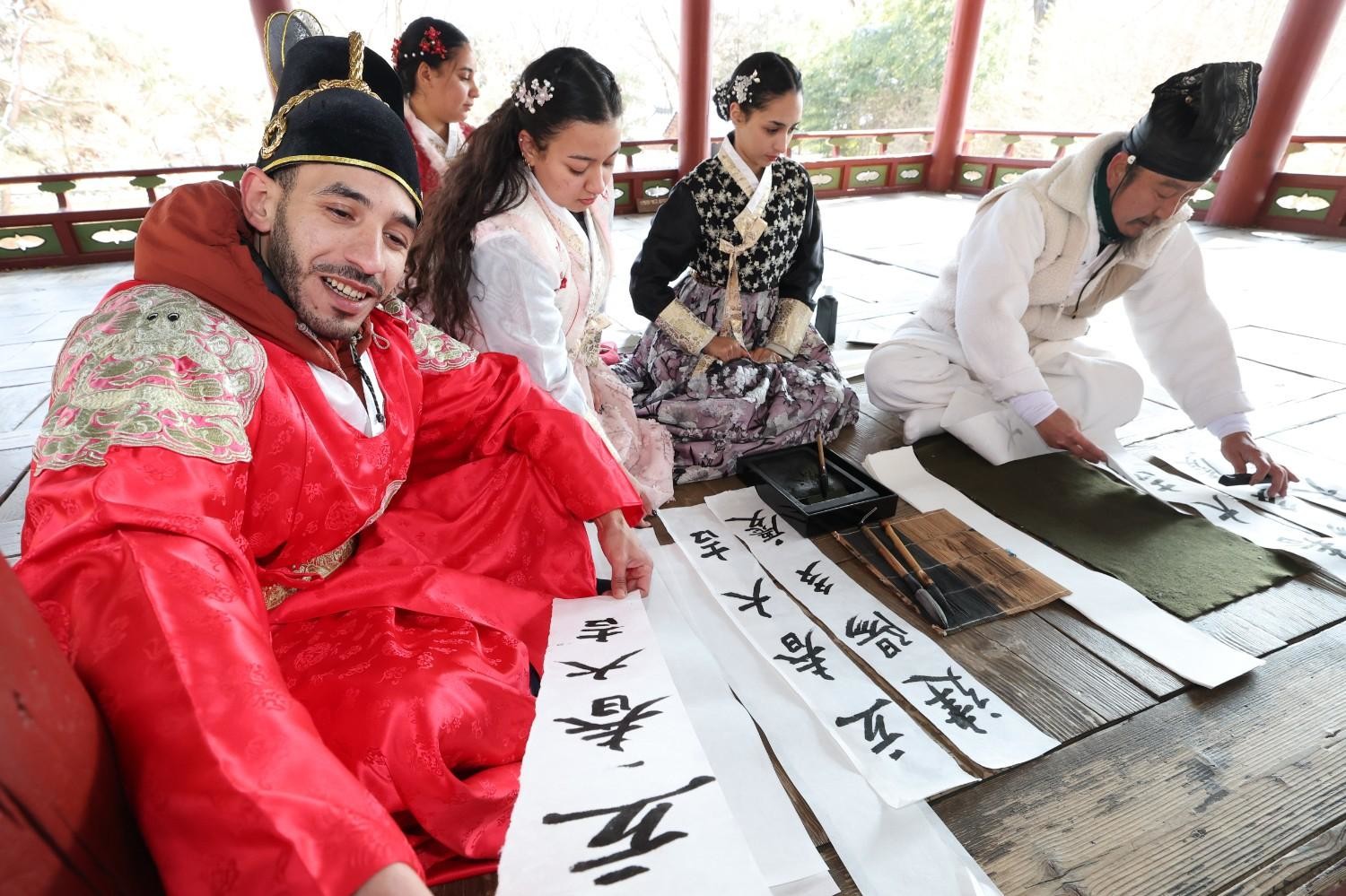 전통 복식을 입은 외국인들이 서예 체험을 하며 붓으로 한글을 쓰고 있다. 한국 문화 체험 프로그램에 참여한 모습이다. / 뉴스1
