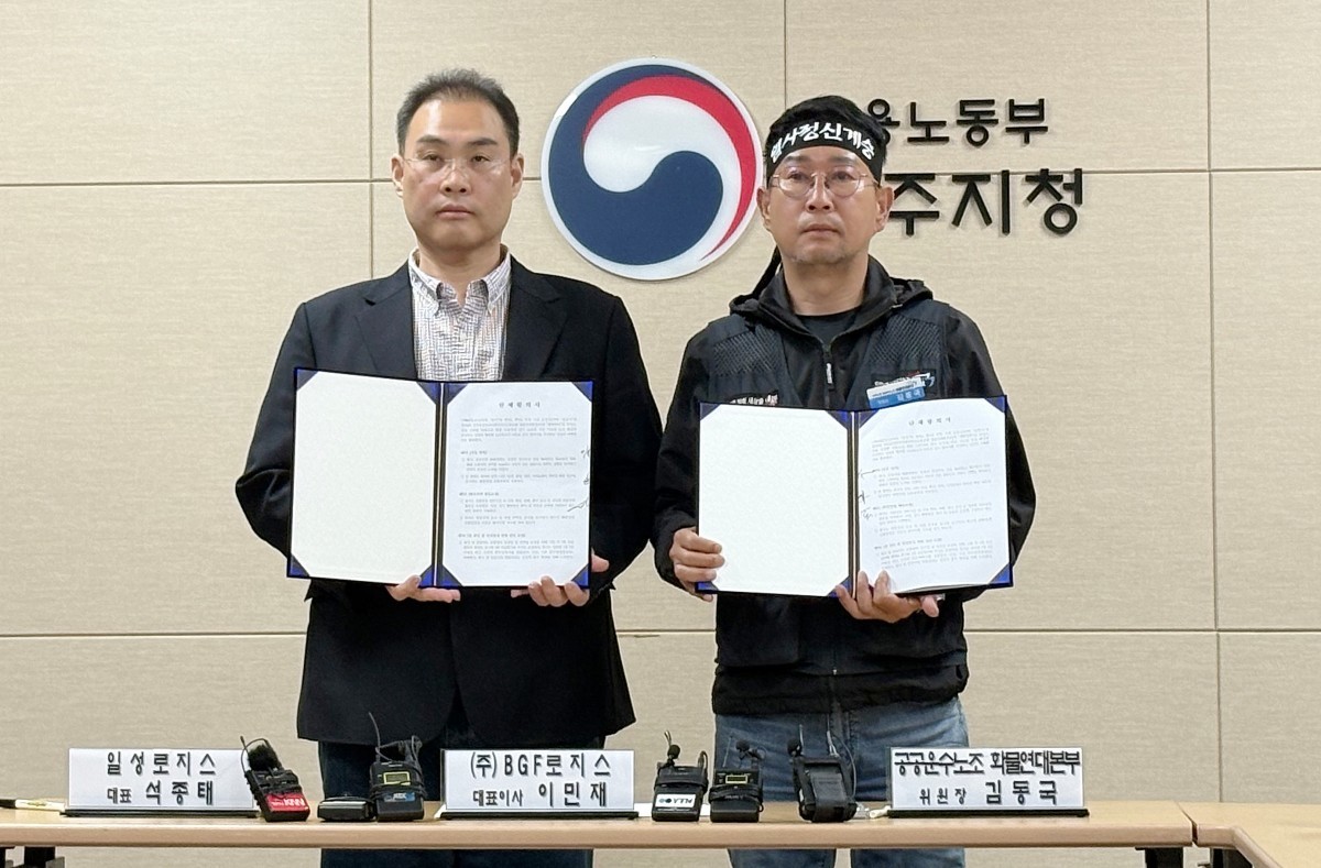 CU BGF 로지스 이민재 대표(왼쪽)와 민주노총 화물연대 김동국 위원장이 지난달 30일 경남 진주시 고용노동부 진주지청에서 열린 조인식에서 단체합의서를 들어보이고 있다.