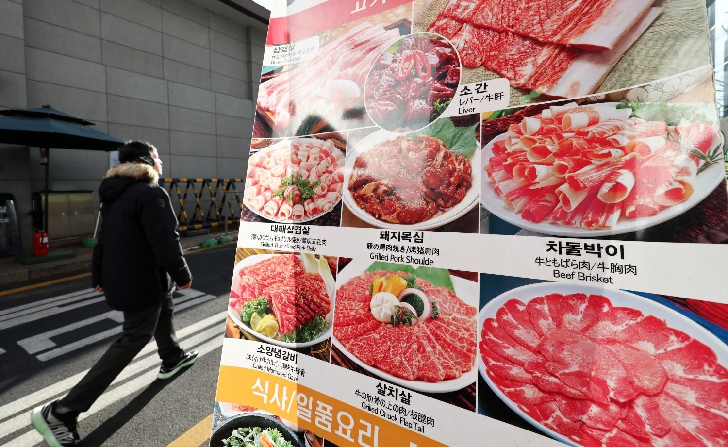 길거리에서 외국인이 다양한 한국 고기 요리 메뉴 사진을 보며 선택하는 모습이 한국 외식 문화의 매력을 전달한다. / 뉴스1