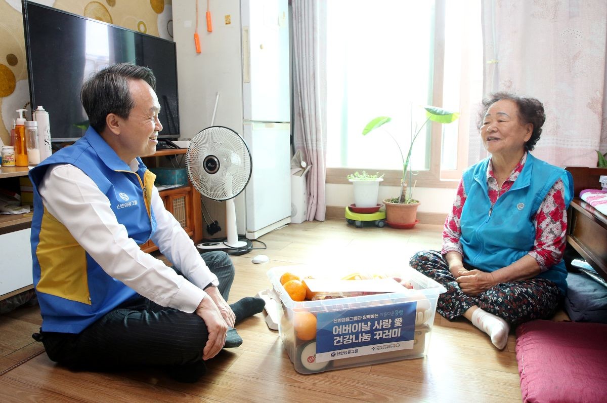 이날 제작한 과일키트 전달을 위해 직접 가정에 방문한 진옥동 신한금융그룹 회장(왼)이 어르신과 담소를 나누고 있다. / 신한금융 제공